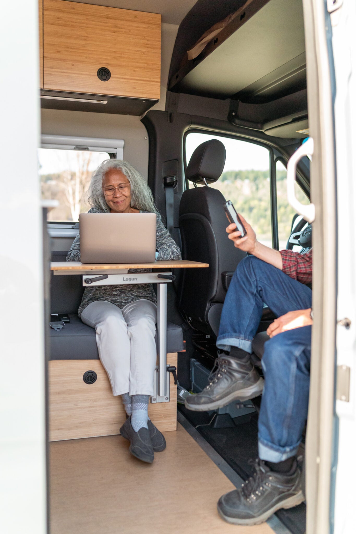 Des voyageurs travaillent à une table Lagun à l’intérieur d’un camping-car.